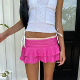 Person wearing a white top and pink skirt with a blurred background
